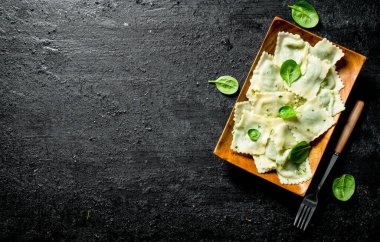 Ravioli bir tabakta sığır eti ile. Siyah rustik arka plan üzerinde