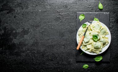Ravioli çatallı bir tabakta. Siyah rustik arka plan üzerinde