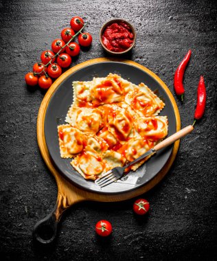 Soslu ravioli, biber ve domates. Siyah rustik arka plan üzerinde