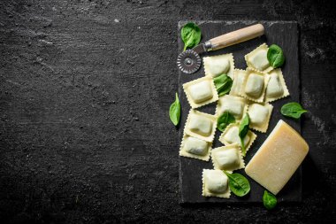 Ispanak ve peynirli çiğ ravioli. Siyah rustik arka plan üzerinde