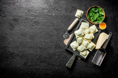 Bir kesme Kurulu otlar ve Parmesan peyniri ile Ham Ravioli. Siyah rustik arka plan üzerinde