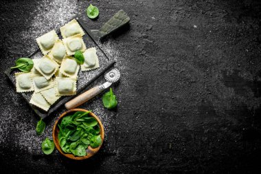 Ispanaklı çiğ ravioli. Siyah rustik arka plan üzerinde