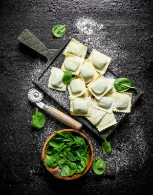 Ispanaklı çiğ ravioli. Siyah rustik arka plan üzerinde