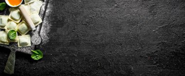 Ravioli çiğ bir kesme Tahtası üzerinde et ile. Siyah rustik arka plan üzerinde