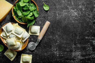 Ravioli parmesan ve ıspanak ile çiğ. Koyu rustik arka plan üzerinde