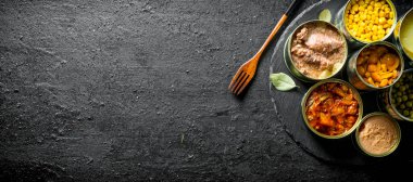 Konserve gıda açık metal konserve çeşitleri. Siyah rustik arka plan üzerinde