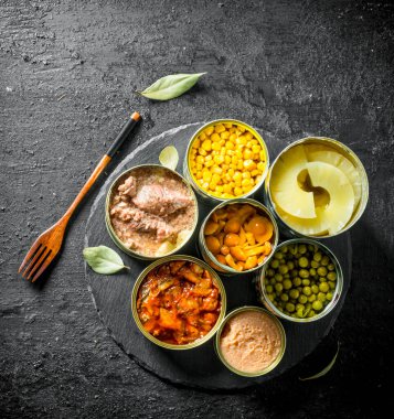 Konserve gıda açık metal konserve çeşitleri. Siyah rustik arka plan üzerinde