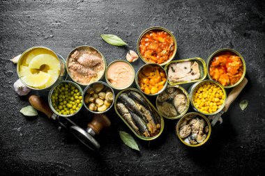 Açık kantlar içinde çeşitli konserve gıda. Siyah rustik arka plan üzerinde