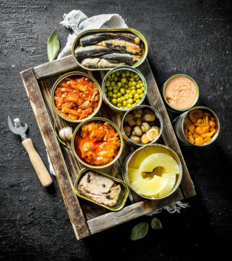 Tepside konserve çeşitli açık konserve konserve ler. Siyah rustik arka plan üzerinde