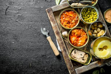 Tepside konserve çeşitli açık konserve konserve ler. Siyah rustik arka plan üzerinde