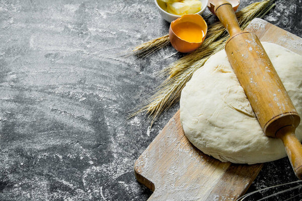 The finished dough with a rolling pin and spikelets. On rustic background