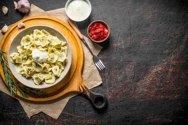 stock image Dumplings with tomato paste and sour cream. On dark rustic background