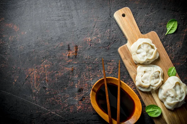 stock image Dumplings manta on a cutting Board with soy sauce. On dark rustic background