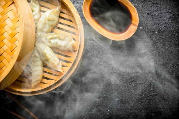 热的中国传统格扎饺子在竹蒸锅与酱油 在质朴的背景 — 图库照片