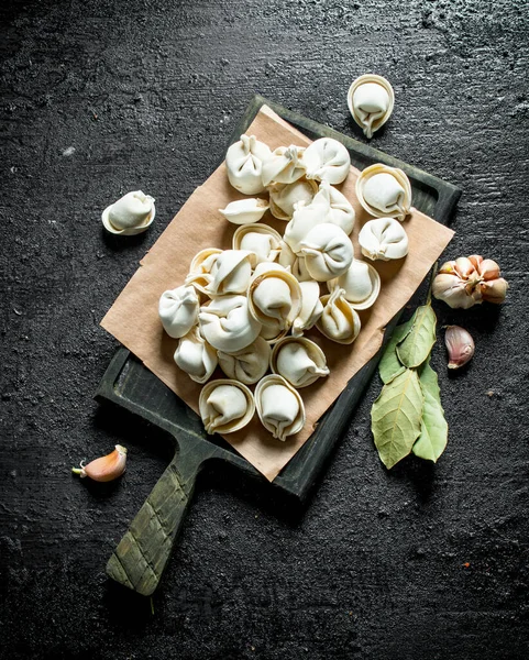 stock image Homemade raw dumpling with garlic cloves and Bay leaf. On black rustic background