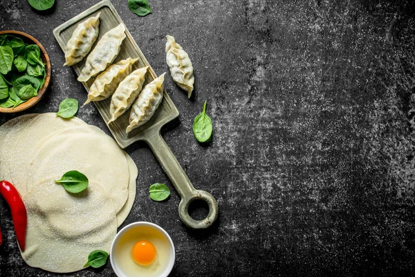 stock image Rolled out dough for making homemade raw gedza dumplings. On dark rustic background