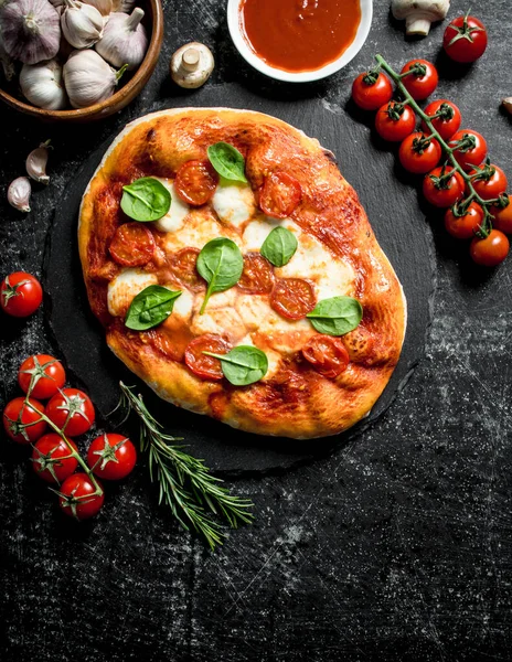 stock image Homemade pizza with cherry tomatoes, spinach and garlic. On dark rustic background