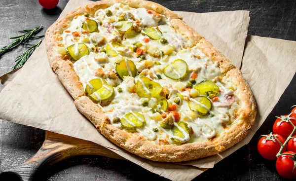 Vegetable pizza on paper with rosemary. On rustic background