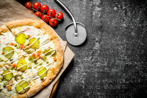 Vegetable pizza on paper. On dark rustic background