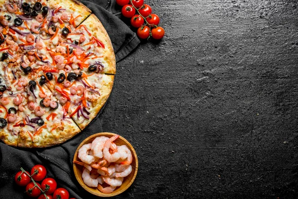 Karidesli ve zeytinli deniz pizzası. Siyah rustik arka plan üzerinde