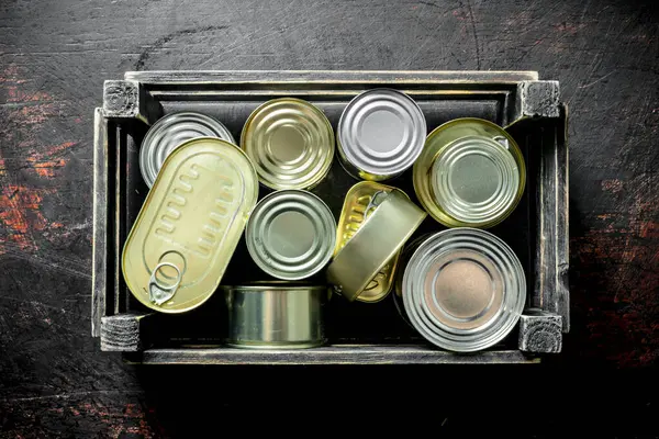 箱の中の閉じた缶の中の缶詰の食べ物 暗い素朴な背景に — ストック写真