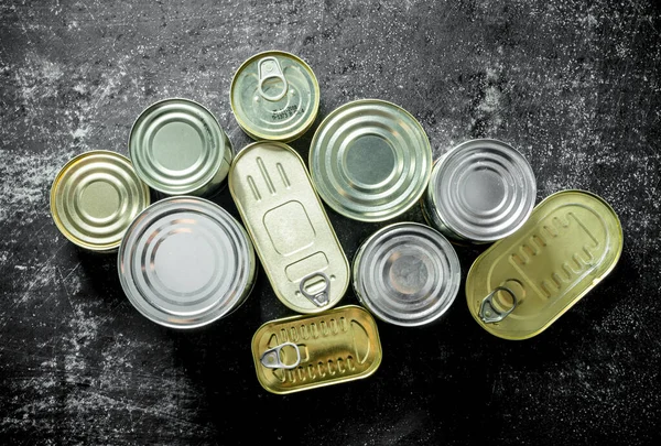 缶詰の食品と閉じたスズ缶のグループ 暗い素朴な背景に — ストック写真