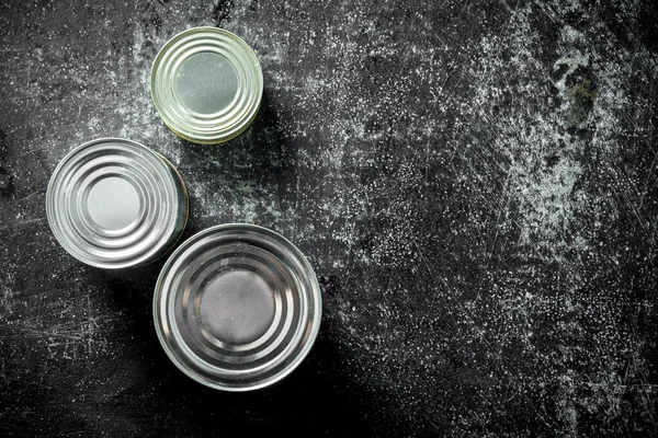 stock image Canned food in closed cans. On dark rustic background