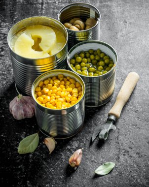 Konserve ananas, yeşil bezelye, mısır ve açık konserve mantar. Koyu rustik arka plan üzerinde