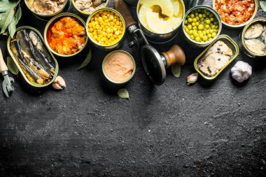 Konserve gıda farklı ayarlayın. Siyah rustik arka plan üzerinde