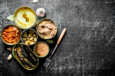 Konserve yiyecek konserveleri farklı türde ayarlayın. Koyu rustik arka plan üzerinde