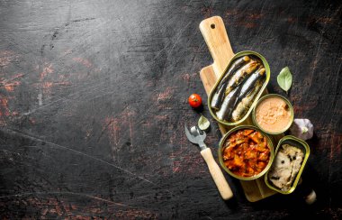 Kesme Tahtası'nda konserve konserve konserveleri açın. Koyu rustik arka plan üzerinde