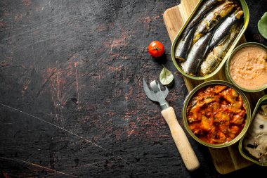 Kesme Tahtası'nda konserve konserve konserveleri açın. Koyu rustik arka plan üzerinde