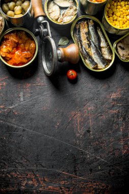 Konserve yiyecekleri aç. Koyu rustik arka plan üzerinde