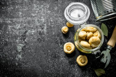 Cam bir kavanozda konserve mantar. Koyu rustik arka plan üzerinde