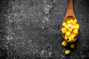 Tahta kaşıkta konserve mısır. Koyu rustik arka plan üzerinde