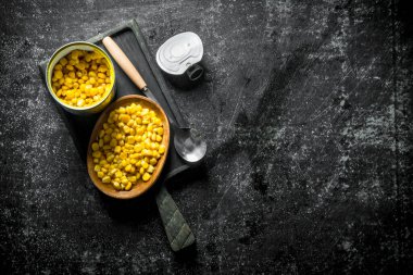 Kesme Tahtası üzerinde konserve mısır ile açık konserve olabilir. Koyu rustik arka plan üzerinde