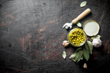 Defne yaprağı ve sarımsak karanfil ile konserve yeşil bezelye. Koyu rustik arka plan üzerinde