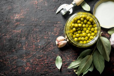 Defne yaprağı ve sarımsak karanfil ile konserve yeşil bezelye. Koyu rustik arka plan üzerinde