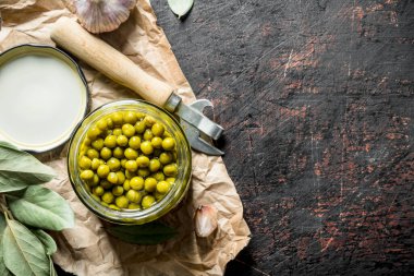 Kağıt üzerinde konserve yeşil bezelye ile açık kavanoz. Koyu rustik arka plan üzerinde