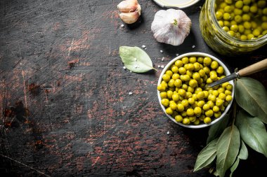 Konserve yeşil bezelye ile açık cam kavanoz. Koyu rustik arka plan üzerinde