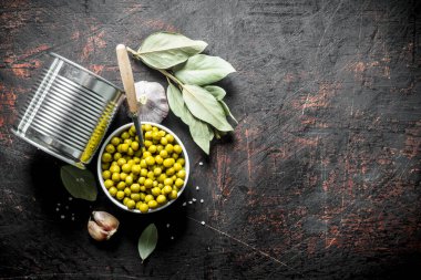 Konserve yeşil bezelye bir kase bir konserve konserve konserve konserve ve Defne yaprağı ile. Koyu rustik arka plan üzerinde
