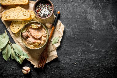 Ekmek dilimleri ile kağıt üzerinde bir konserve et. Siyah rustik arka plan üzerinde