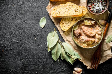 Ekmek dilimleri ile kağıt üzerinde bir konserve et. Siyah rustik arka plan üzerinde