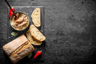 Dilimlenmiş ekmek ve acı biber ile konserve et. Siyah rustik arka plan üzerinde
