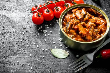 Taze kiraz domates ile bir konserve sprat. Siyah rustik arka plan üzerinde