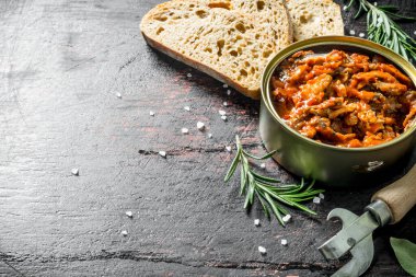 Ekmek ve biberiye dilimleri ile bir konserve içinde domates sosu içinde Sprat. Koyu rustik arka plan üzerinde