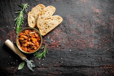 Ekmek ve biberiye dilimleri ile bir konserve içinde domates sosu içinde Sprat. Koyu rustik arka plan üzerinde