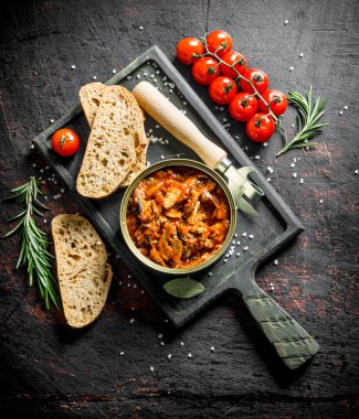 Kesme Tahtası üzerinde domates sosu içinde sprat ile açık konserve olabilir. Koyu rustik arka plan üzerinde