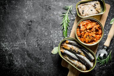 Bir açacağı ve biberiye ile bir kesme Tahtası üzerinde konserve balık açık konserve konserve. Koyu rustik arka plan üzerinde
