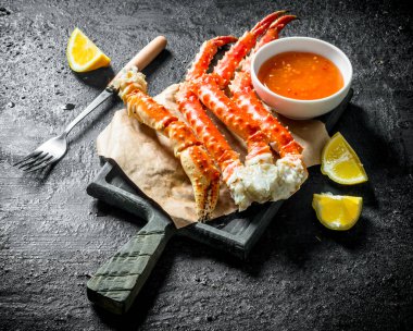 Limon dilimleri ve sos ile kağıt üzerinde Yengeç. Siyah rustik arka plan üzerinde